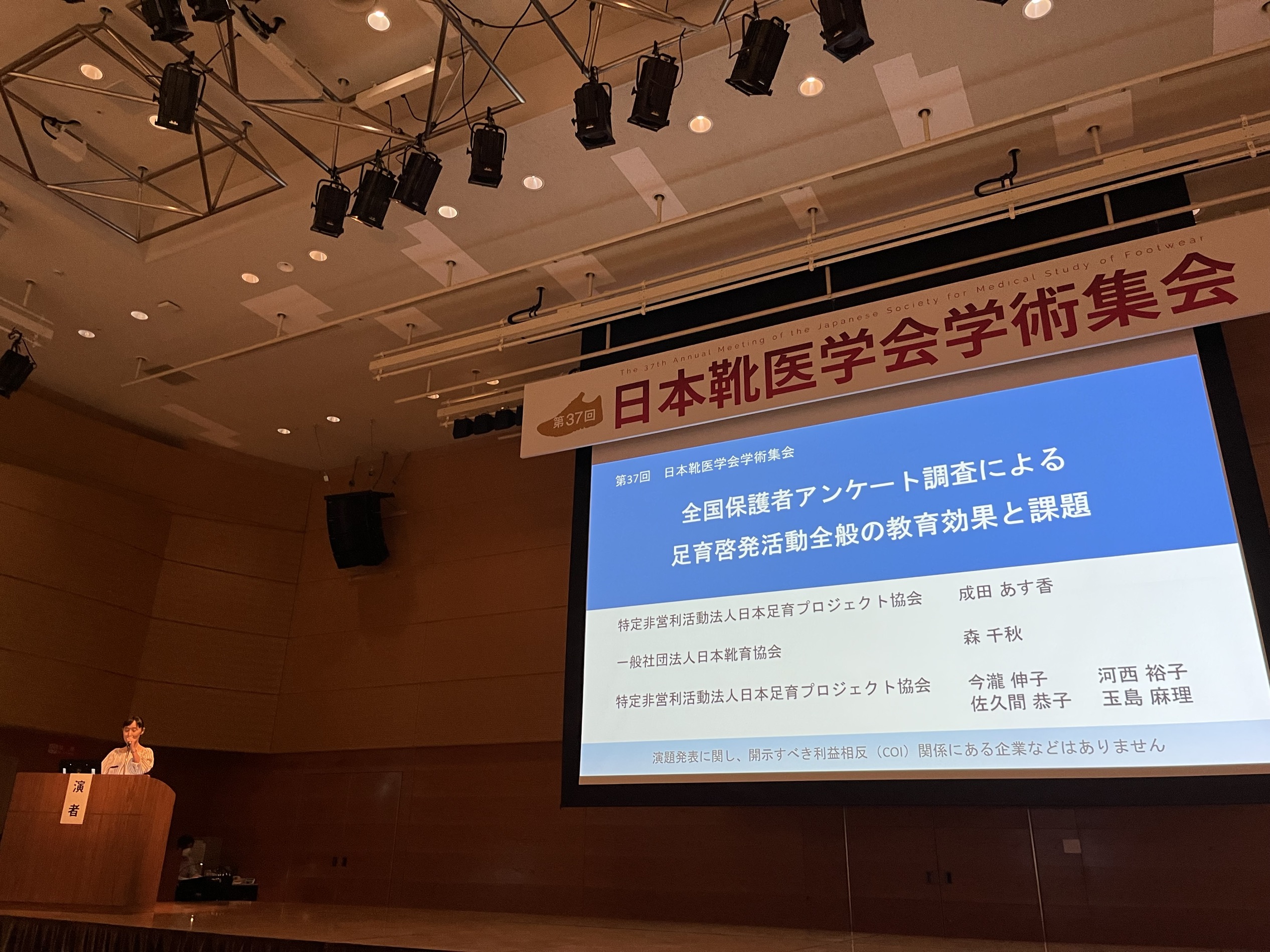 靴医学会が開催されたホールで発表する成田
