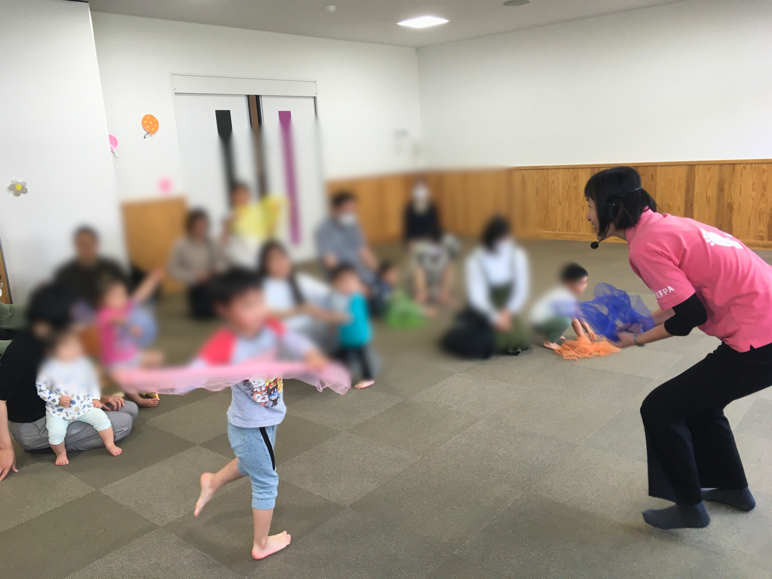 足育講座のはじまりに、カラーシフォンを使ってアイスブレイクをする様子。
自由に体を動かして遊ぶことが、足育の第一歩であると伝える場面。