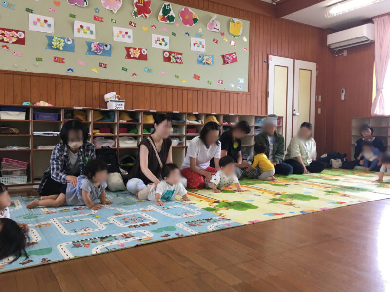 平和が丘幼稚園の子育て支援「すくすくクラブ」の講座風景。お母さんがわが子の背中や腰に触れて、撫でたり揺らしたりする遊びをしている様子。(2025年5月21日)