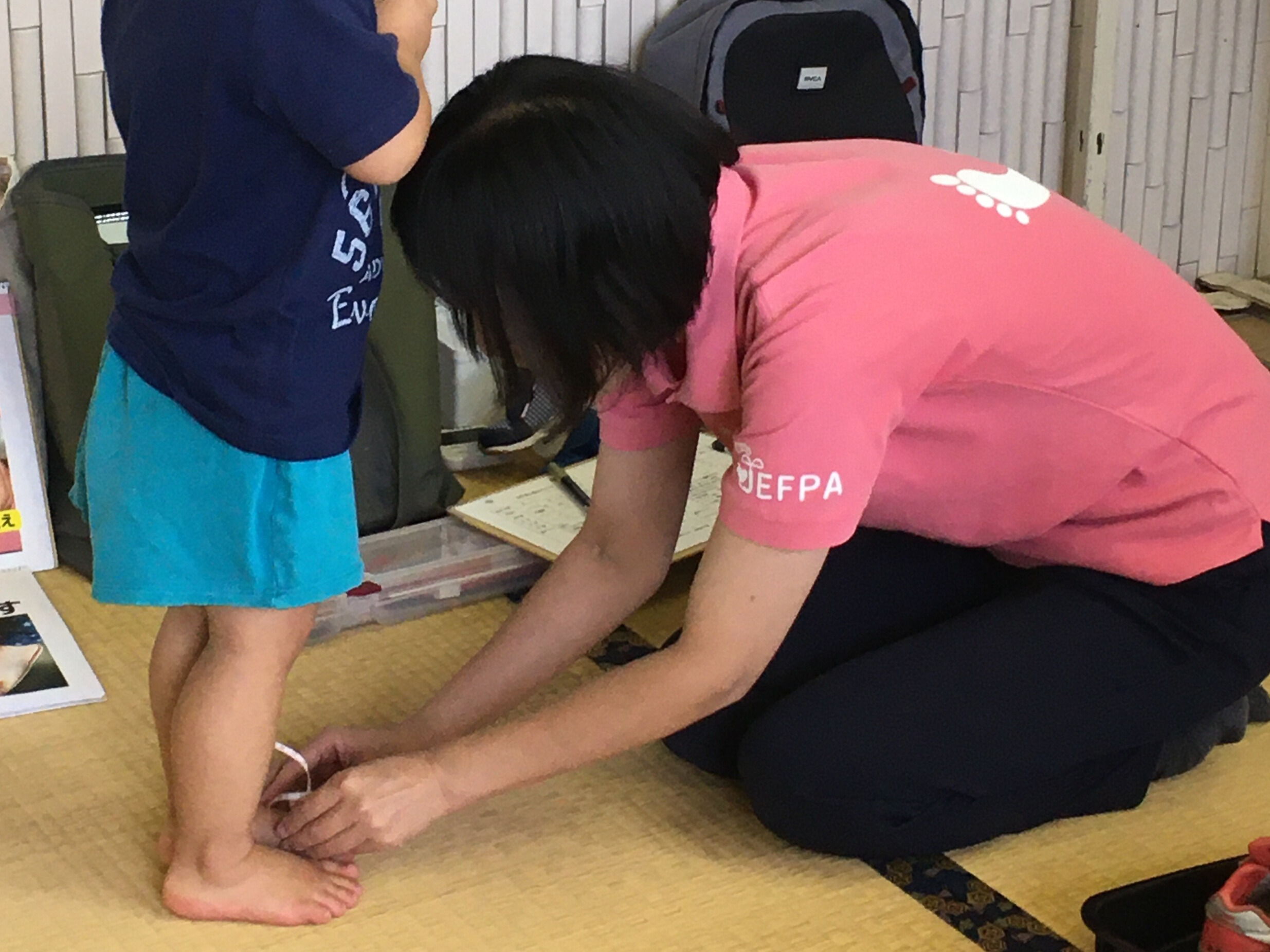 足育ブースで、子どもの足のサイズをメジャーで測定している様子。講師が膝をついて計測を行っている(2025年6月1日 門川町子育て応援フェスティバル)