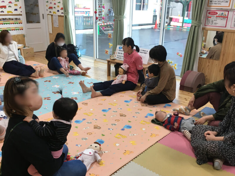 足育講座の様子。靴下を脱いで床に座り、自分の足の指を動かしたり、子どもの足に触れたりしながら、グー、チョキ、パーと動かしている場面(2026年4月10日)