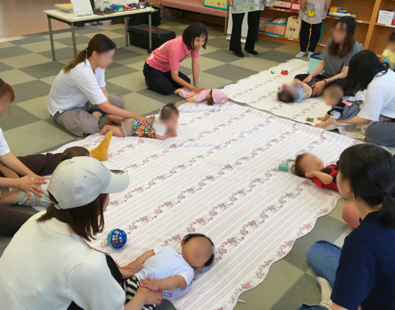 森永児童館子育て支援センターの足育講座で、寝返りやはいはいをしやすい体づくりにつながるふれあい遊びを、赤ちゃんと一緒に体験している様子